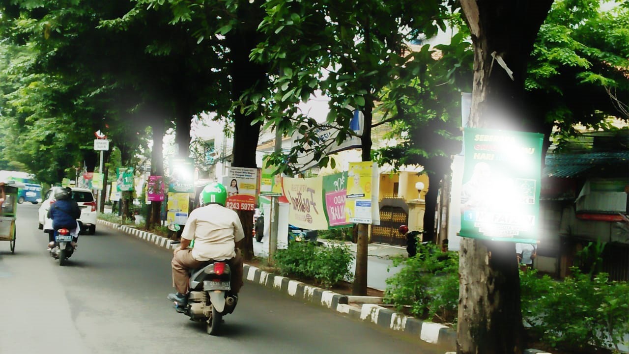 Ilustrasi,spanduk bergambar caleg yang dipaku di pohon 