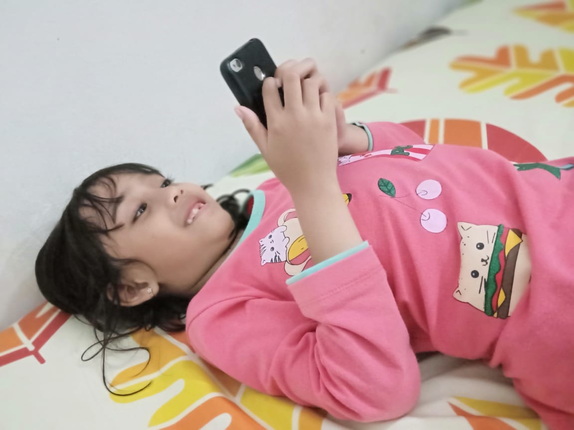Anak sedang asik bermain game di hadphone