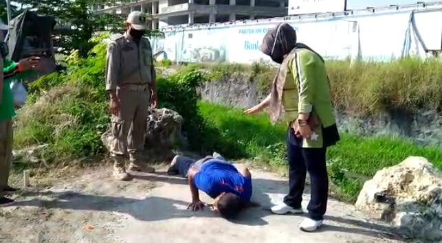 Petugas menghukum pelanggar PSBB